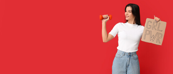 Young woman holding dumbbell and paper with slogan GRL PWR on red background with space for text....