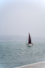 A solo sailing boat on sea and misty background.