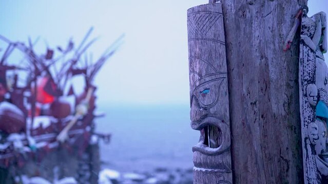 Old african woodmask on an old wood pole at the sea coast in snowfalling Iceland recycling house
