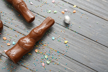 Chocolate bunnies, Easter egg in foil and sprinkles on grey wooden background