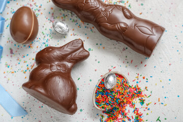 Chocolate Easter eggs with sprinkles and bunnies on grey background