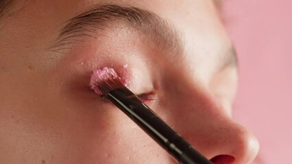 Eye shadow makeup to the upper eyelid, close-up. Makeup artist applies a bright eye shadow with a makeup brush.Tutorial master class of professional makeup. 