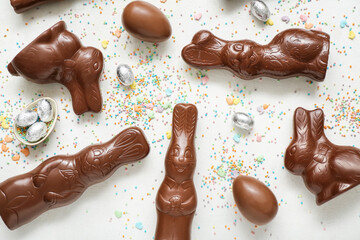 Chocolate Easter eggs with sprinkles and bunnies on white background