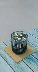glass cup with water on cup holder on wooden table with blue weathered paint, rest and drinking theme