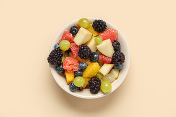 Bowl of fresh fruit salad on beige background