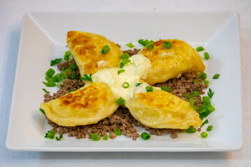 Traditional Ukrainian pierogi grilled in butter and served with minced meat and cream, decorated...