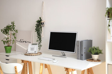 Blank computer monitor with telephone on table in light office