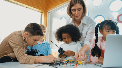 Teacher teach and explain students about digital electrical tool or car model. Diverse kid learn...