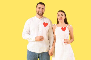 Lovely couple with paper hearts on yellow background. Valentine's Day celebration