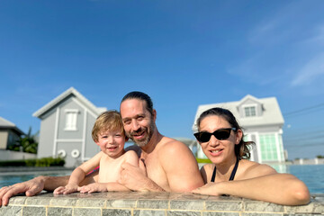Obraz premium Happy Caucasian White people family, father, mother and son, are enjoy playing water in the swimming pool.