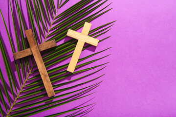 Wooden crosses with palm leaf on purple background
