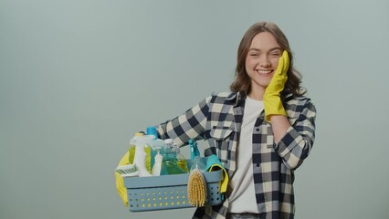 Portrait of a Surprised Young Woman in Yellow Gloves,Holding a Box With Cleaning Products on the Gray Background.A Female Housewife is Preparing to Clean. Home Office Organization Tips.