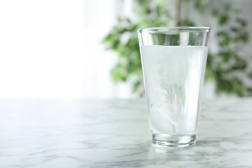 Glass of water with effervescent tablet on marble table indoors, space for text