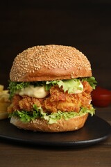 Delicious burger with crispy chicken patty on wooden table, closeup
