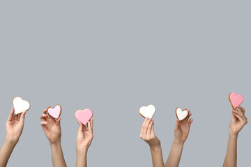 Women with heart-shaped cookies on grey background. Valentine's Day celebration