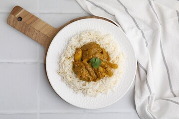 Delicious chicken curry with rice on white tiled table, top view