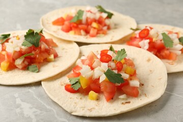 Fototapeta na wymiar Delicious tacos with vegetables and parsley on grey marble table, closeup