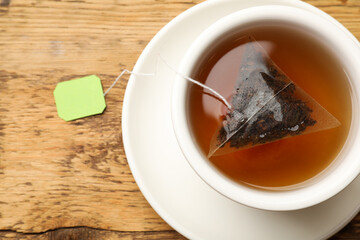 Tea bag in cup on wooden table, top view