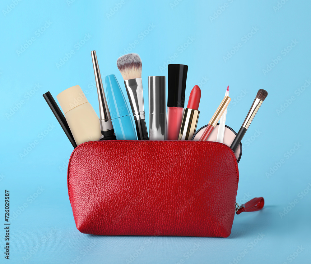 Wall mural Cosmetic bag filled with makeup products on light blue background