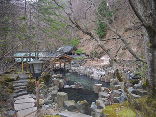 Traditional Japanese onsen hot spring Rotenburo open air bath on mountain river in the forest, Takaragawa, Japan