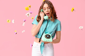 Young woman talking by retro telephone with beautiful flowers on pink background. International Women's Day