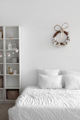 Interior of light bedroom with Easter wreath and shelf unit