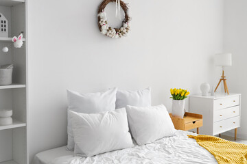 Interior of light bedroom with Easter wreath and tulips - obrazy, fototapety, plakaty