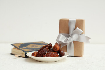 Gift box with dried dates and Koran for Ramadan on white table