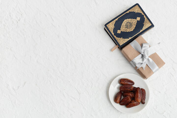 Gift box with dried dates and Koran for Ramadan on white table