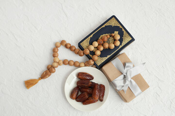 Gift box with dried dates, Koran and prayer beads for Ramadan on white table
