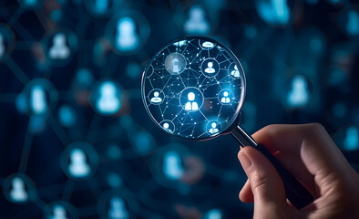 hand holding up a magnifying glass with a lot of people on the screen 