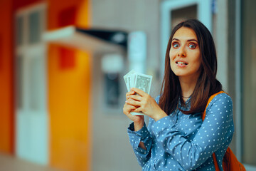 Cheerful Girl Holding Money in front of Atm Machine. Happy person winning extra dollars with...