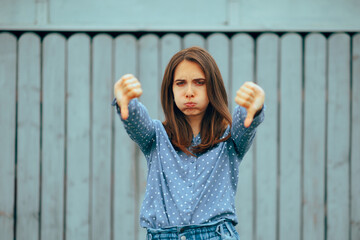 Unhappy Woman with Thumbs Down Feeling Outraged. Millennial girl giving negative feedback to a situation
