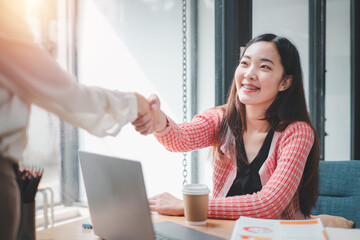 A confident businesswoman engaging in a firm handshake during a professional meeting in a sunny office environment.