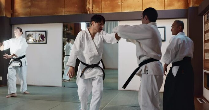 Students, karate class or sensei teaching martial arts in dojo for fitness, discipline or self defense for combat. Demonstration, master or kung fu teacher training a person for fighting education