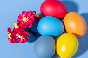 Colorful eggs, symbolizing Easter, on a colorful background and flowers
