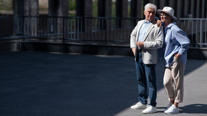 Fototapeta premium Stylish mature couple. Gray-haired man and woman holding hands while walking around the city. 