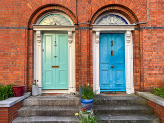 Fototapeta na wymiar Colorful green and blue doors in red brick wall with stairs, Dalkey, Ireland 