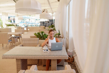 Woman coffee cafe laptop sea. Modern businessman in white uniform working on laptop in coffee shop. Woman sitting at a coffee shop with mobile phone drinking coffee.