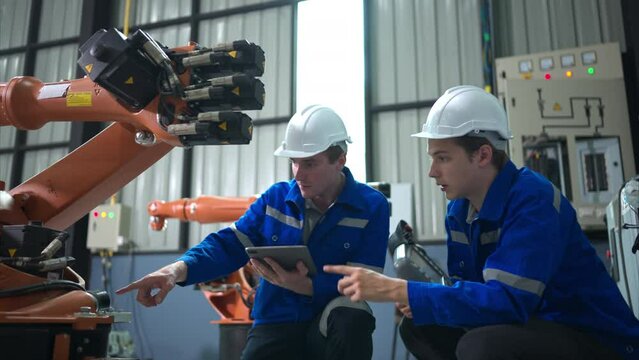 Engineer and technician working with robot arm in factory. Industry and engineering concept.