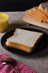 Slices of Toast Loaf White Bread (Shokupan or Roti Tawar) for Breakfast on a Black plate, Served with margarine and jam.