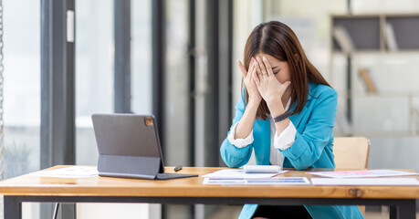 Shot of stressed, sleepy and bored business asian woman sitting at a desk on laptop for a long time and looking worried, tired and overwhelmed