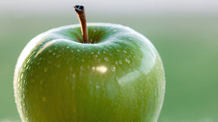 Close up of green apple with water droplets on the surface.