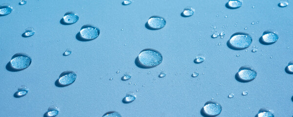 Water background with drops on a blue surface, wet pattern. Spa concept, texture of cosmetics, gel, serum. Aqua spray, banner