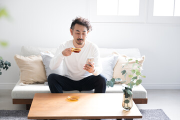 Bearded man drinking coffee in living room with green foreground blur and copy space