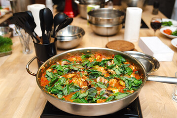 Fresh Basil Tomato Sauce in Cooking Pan. Homemade tomato sauce with fresh basil, vegetables, and spices cooking in a stainless steel pan on a kitchen stove.