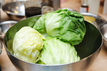 Fresh Iceberg Lettuce in Stainless Steel Bowl. Three fresh heads of iceberg lettuce in a large...