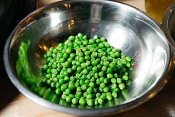 Fresh Green Peas in a Stainless Steel Bowl. A bowl of vibrant green peas reflecting healthy eating and fresh produce, an essential ingredient for nutritious meals.