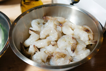 Raw Shrimps Ready for Cooking in Metal BowlRaw Shrimps Ready for Cooking in Metal Bowl. A stainless steel bowl filled with fresh raw shrimps, with tails on, prepared for culinary recipes in a kitchen 
