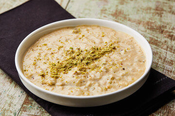 Rice pudding porridge, kheer, khir or firini sweet topping with pistachio served in dish isolated on table top view of arabic dessert food